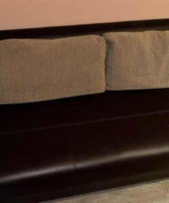 dunkel braune Couch mit zwei beige farbenen Kissen